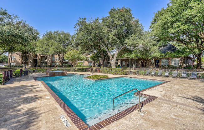 A large outdoor pool surrounded by trees and a fence.