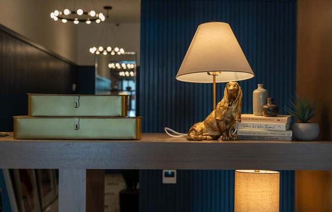 A table with a lamp, a box, a plant, and a sculpture on it.