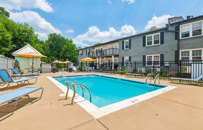 A swimming pool surrounded by chairs and a fence.