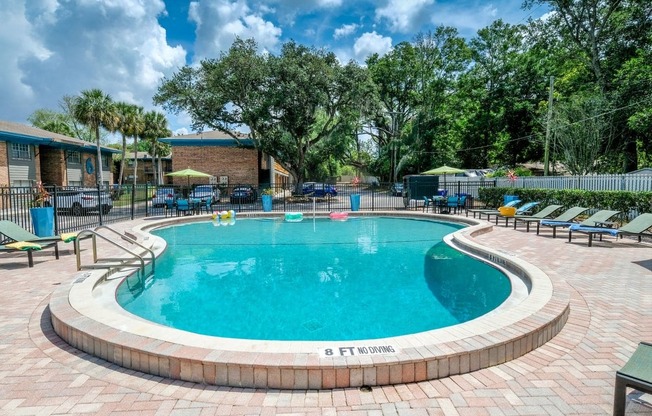 Community pool at the Watermarc Apartments in Lakeland, Fl surrounded by green hedges and iron fencing with gate to parking lot.