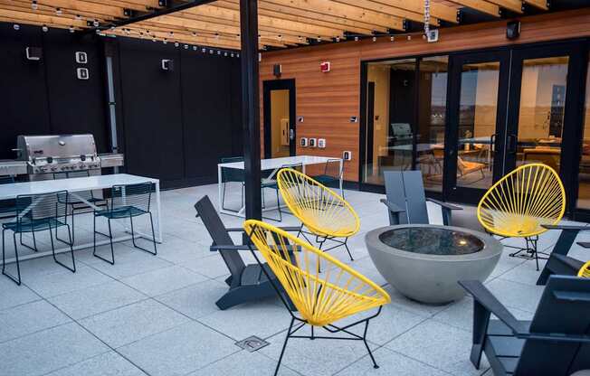 A patio with a fire pit and chairs.