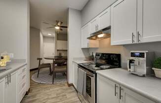 Model Kitchen with White Cabinets and Wood-Style Flooring at Landings at Morrison Apartments located in Gresham, OR.