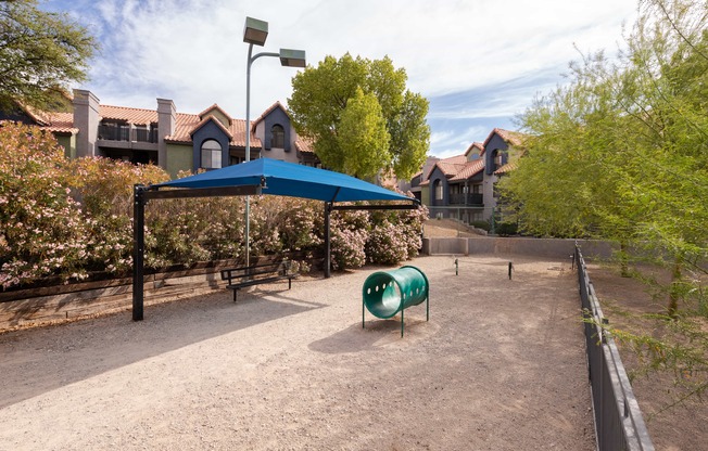 a playground with a blue tent and a green chair     and houses