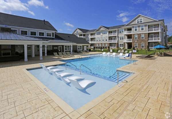 a large swimming pool with chairs in front of an apartment building