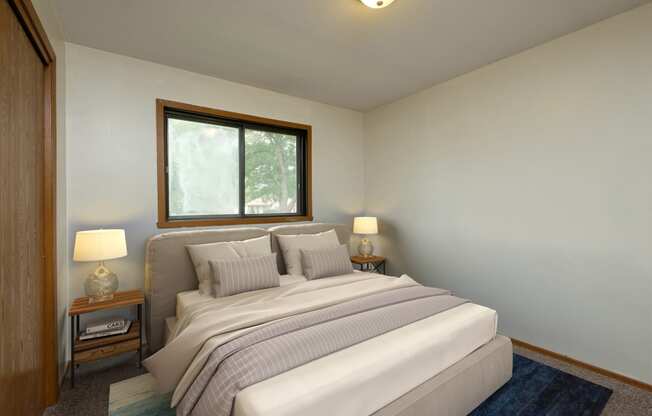 Fargo, ND Gemstone Apartments. A bedroom with a bed and two night stands and a window.