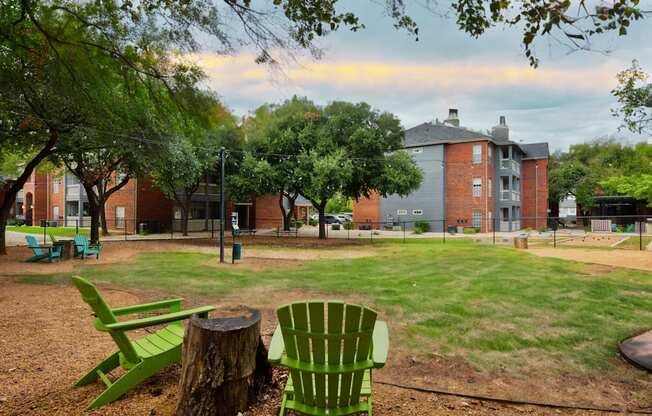 A park with a green chair and a tree stump in the foreground.