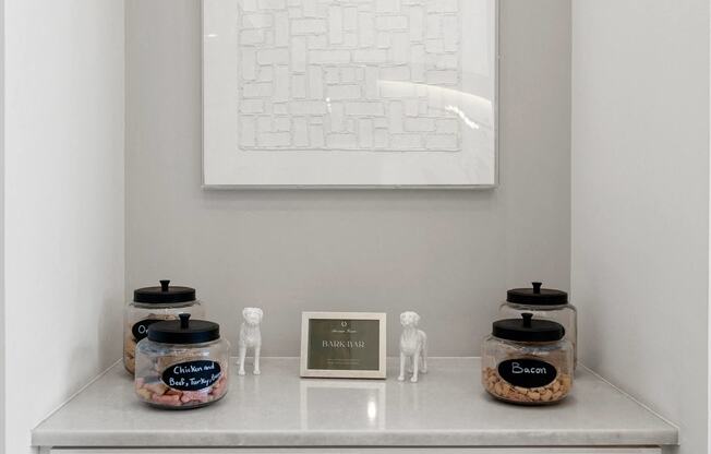 a white shelf with jars and a picture on the wall above it