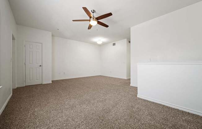 A room with a ceiling fan and carpeted floor.