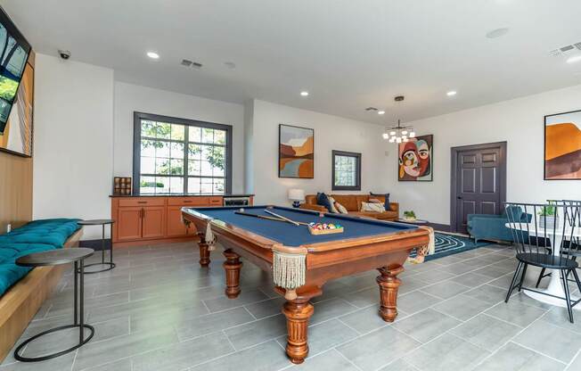 A pool table is in the middle of a room with a blue cushion on it.