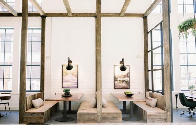 Indoor wooden pergola with wooden beams and two tables with benches on either side and oversized windows at The Merchant Apartments, Charleston, SC, 29403