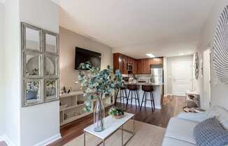 A living room with a white couch and a coffee table with a vase of flowers on it.