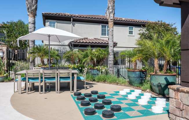 an outdoor checkers game with a table and chairs