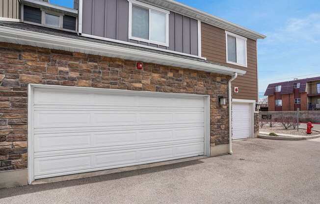A garage door is closed in front of a brick wall.