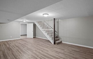 an empty living room with a white staircase and wood flooring