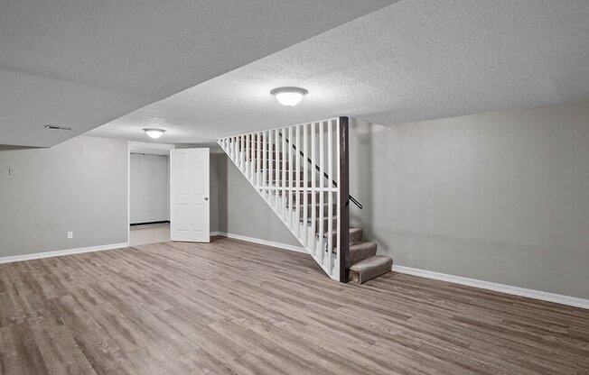an empty living room with a white staircase and wood flooring