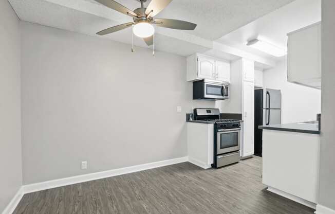 the spacious living room and kitchen with stainless steel appliances and a ceiling fan