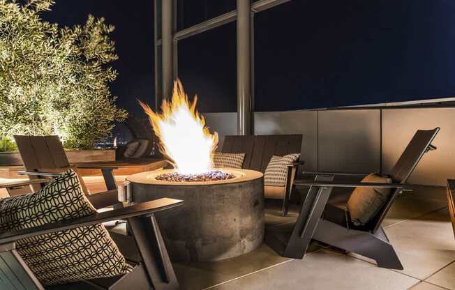 A fire pit in the middle of a patio surrounded by chairs.
