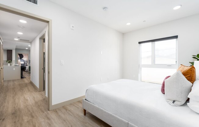 a bedroom with a large white bed and a door to a hallway