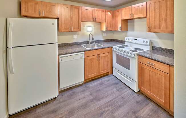 L shaped kitchen with white appliances, light brown cabinets and wood style flooring.at Park View Apartments, Wenatchee