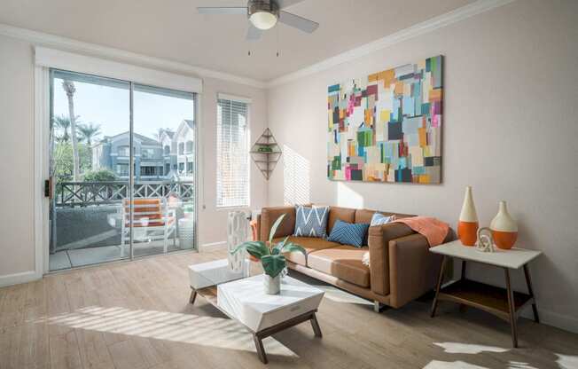 Model Living room with sliding doors to patio, light faux wood floors, leather couch and coffee tables