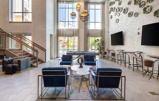 the lobby of a hotel with blue chairs and tables and large windows