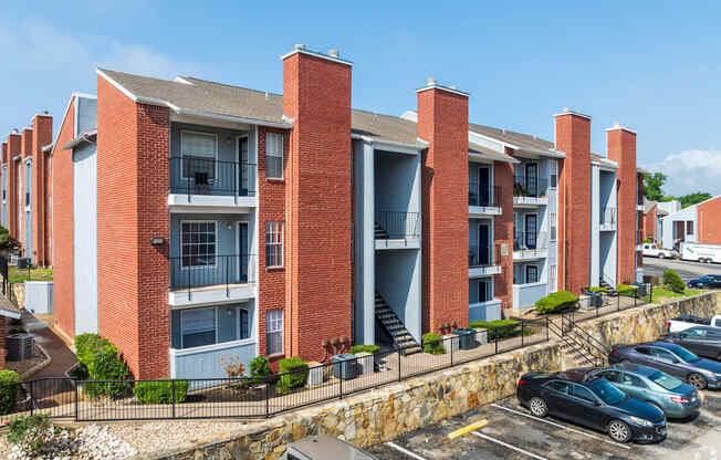 A red brick apartment building with a parking lot in front.