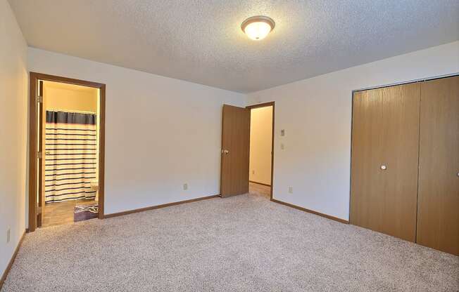 an empty living room with a closet and a door to a hallway. Fargo, ND Kennedy Apartments