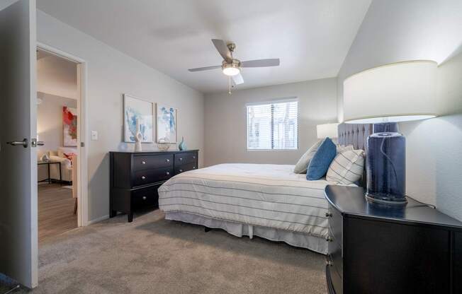 A bedroom with a bed, dresser, and ceiling fan.