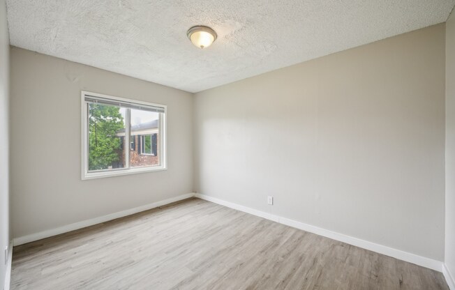 A room with a window and wooden flooring.
