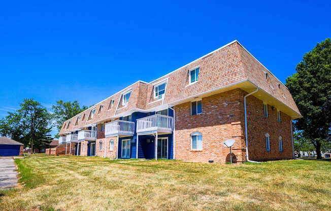 A red brick building with a balcony on the second floor at The Hampton Meadows Apartments, IA,50315