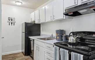 A black refrigerator is in a kitchen with white cabinets.