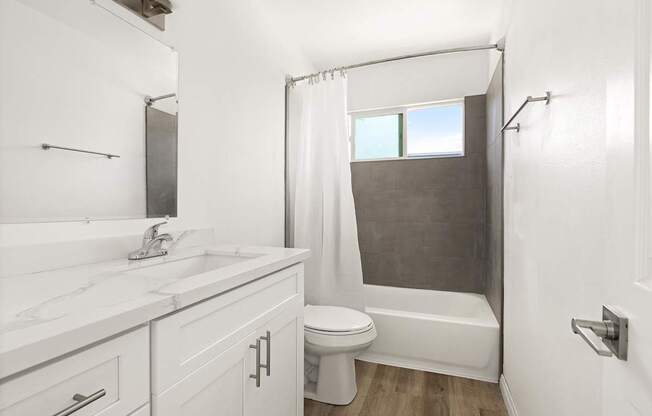 A white bathroom with a toilet, sink, and shower.
