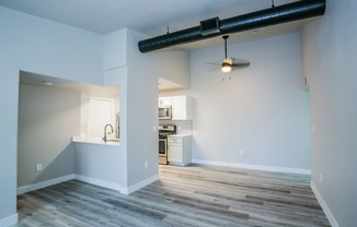 an empty living room with a kitchen in the background
