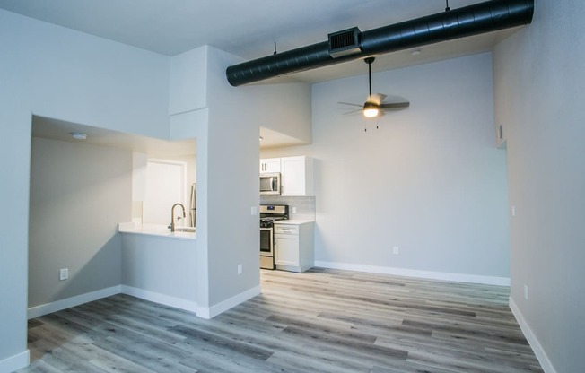 an empty living room with a kitchen in the background