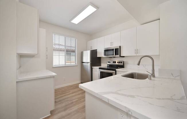 A kitchen with white cabinets and a marble countertop.