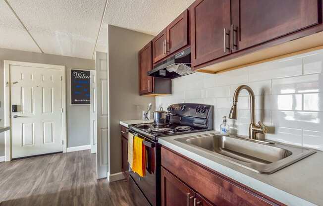 A kitchen with a sink, stove, and cabinets.