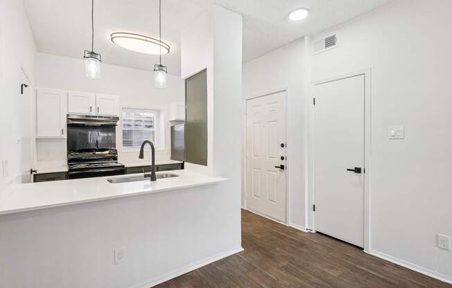 A kitchen with white cabinets and a white countertop with a sink.