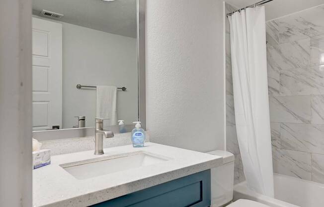 A white sink with a blue bottle of soap on it.