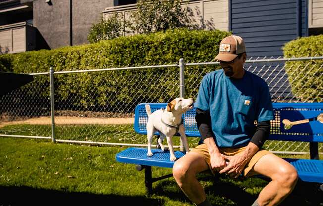 a man sitting on a bench with his dog