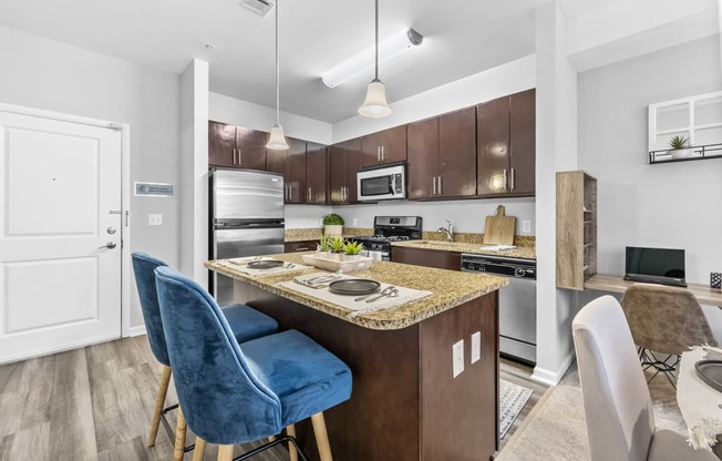 a kitchen with an island with a breakfast bar and two blue chairs  at Harbor Pointe, Bayonne, NJ