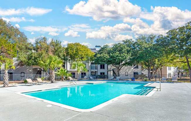 A swimming pool surrounded by trees and buildings.