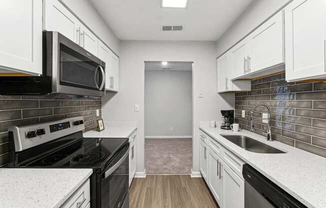 A kitchen with black appliances and white cabinets.