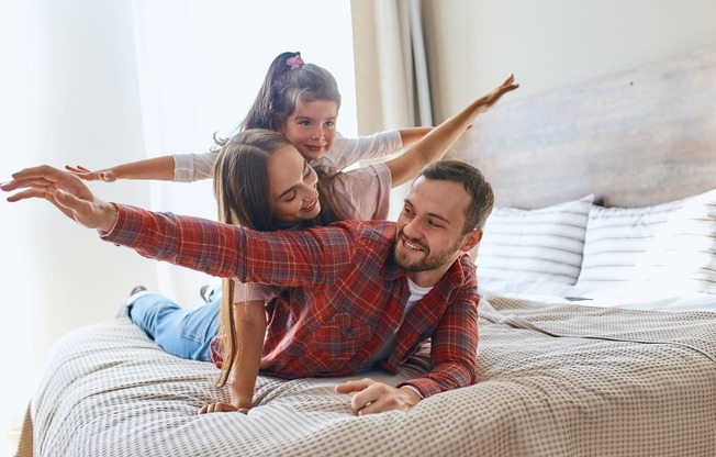 a man and woman laying on a bed with their daughter