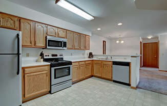 A bright kitchen here at Arbor Ridge featuring warm oak cabinets, white countertops, and stainless steel appliances. The open layout and clean finishes create a spacious, welcoming area for cooking and entertaining.