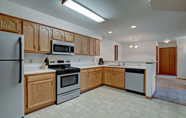 A bright kitchen here at Arbor Ridge featuring warm oak cabinets, white countertops, and stainless steel appliances. The open layout and clean finishes create a spacious, welcoming area for cooking and entertaining.