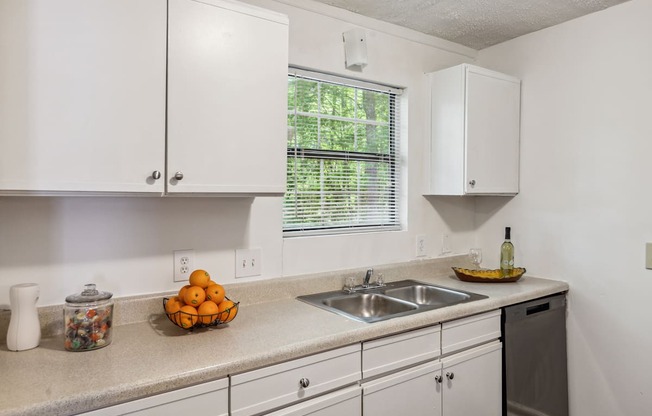 a kitchen with white cabinets and a sink and a window