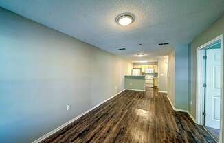 a long hallway with a wood floor and a kitchen