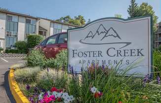 A sign for foster creek apartments with flowers in front of it