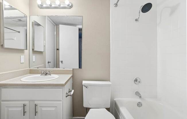 A white bathroom with a sink, toilet, and bathtub.