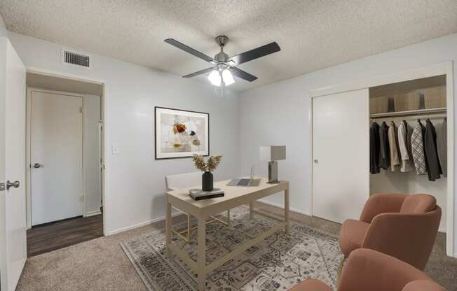 an open living room with a ceiling fan and a closet with clothes hanging